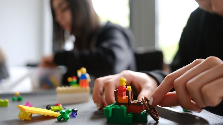 Das Bild zeigt ein Kind, das mit Legofiguren bastelt.